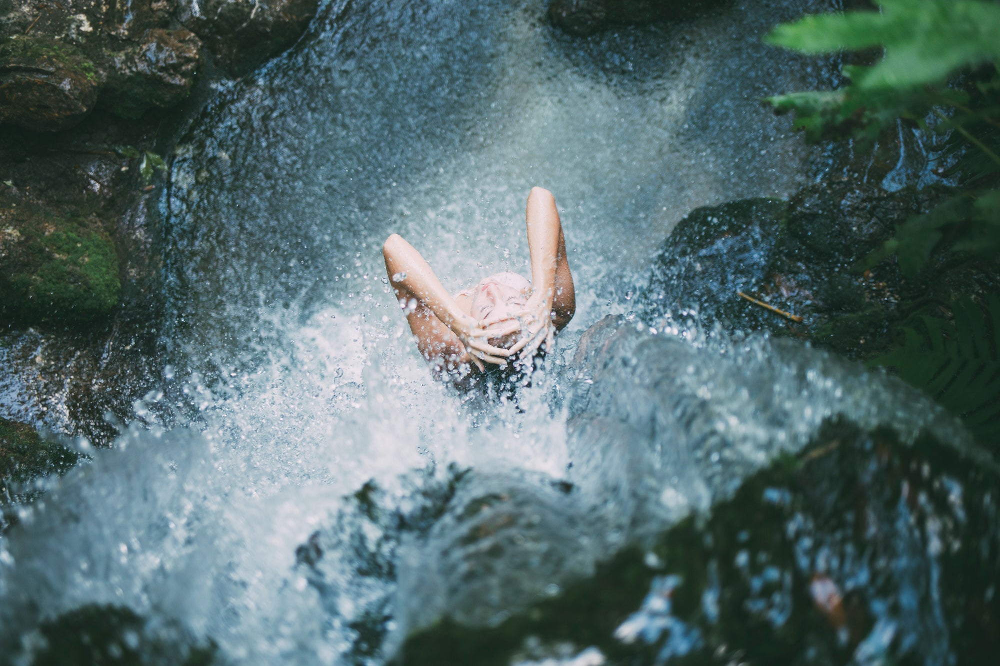 Eine Person steht unter einem Wasserfall